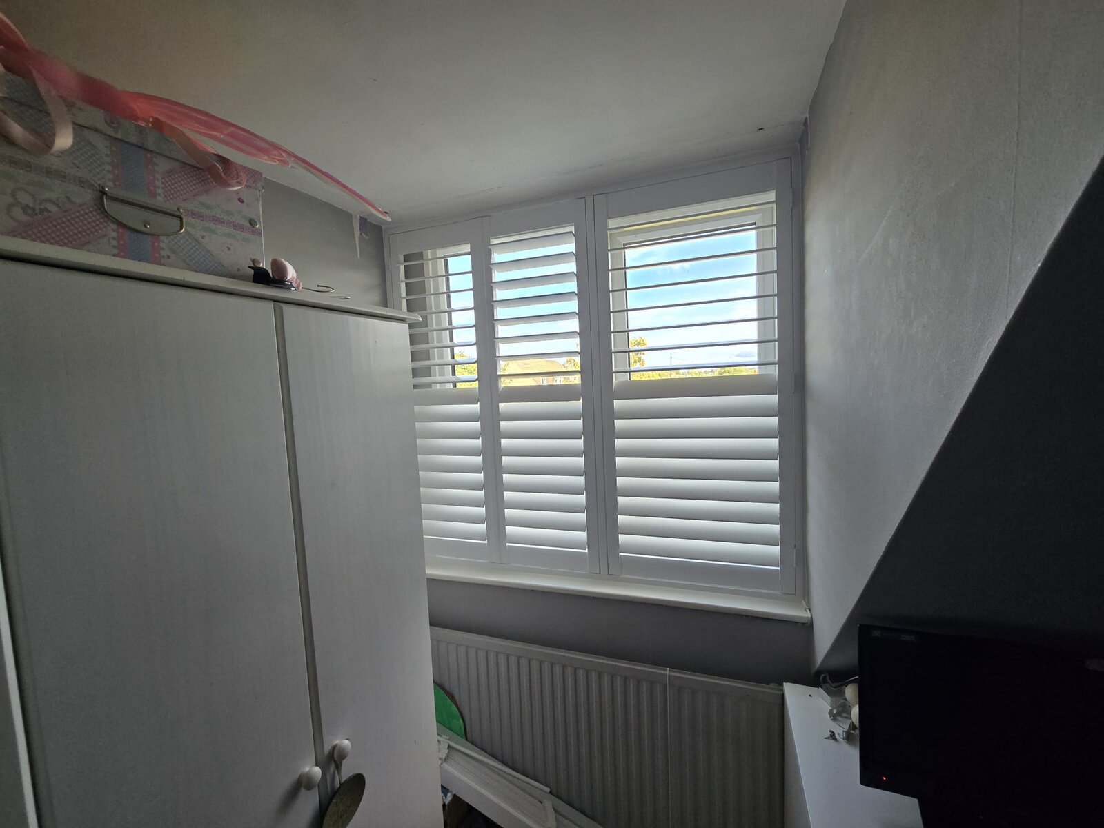 White hardwood shutters with a hidden split on a Chacombe bedroom window, top louvres open and lower louvres closed