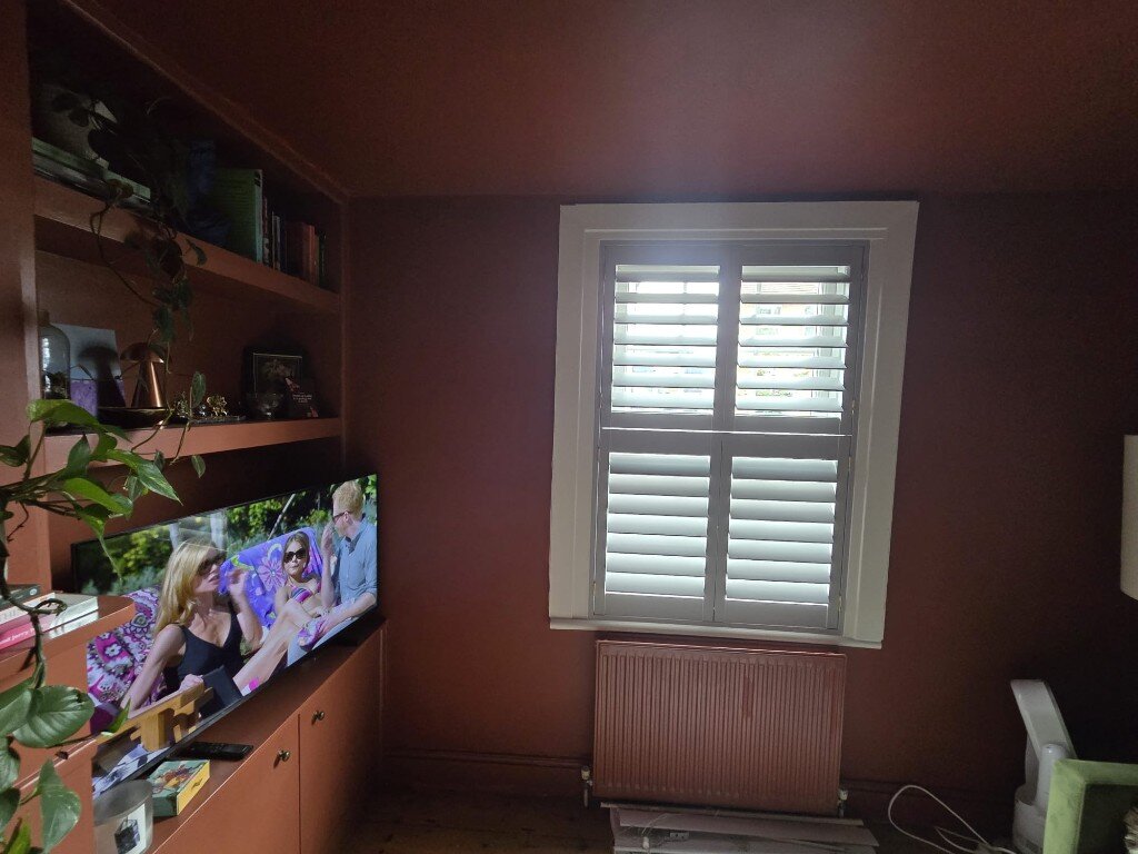 Croydon living room with Slate Grey tier-on-tier shutters, terracotta walls, TV unit and painted radiator