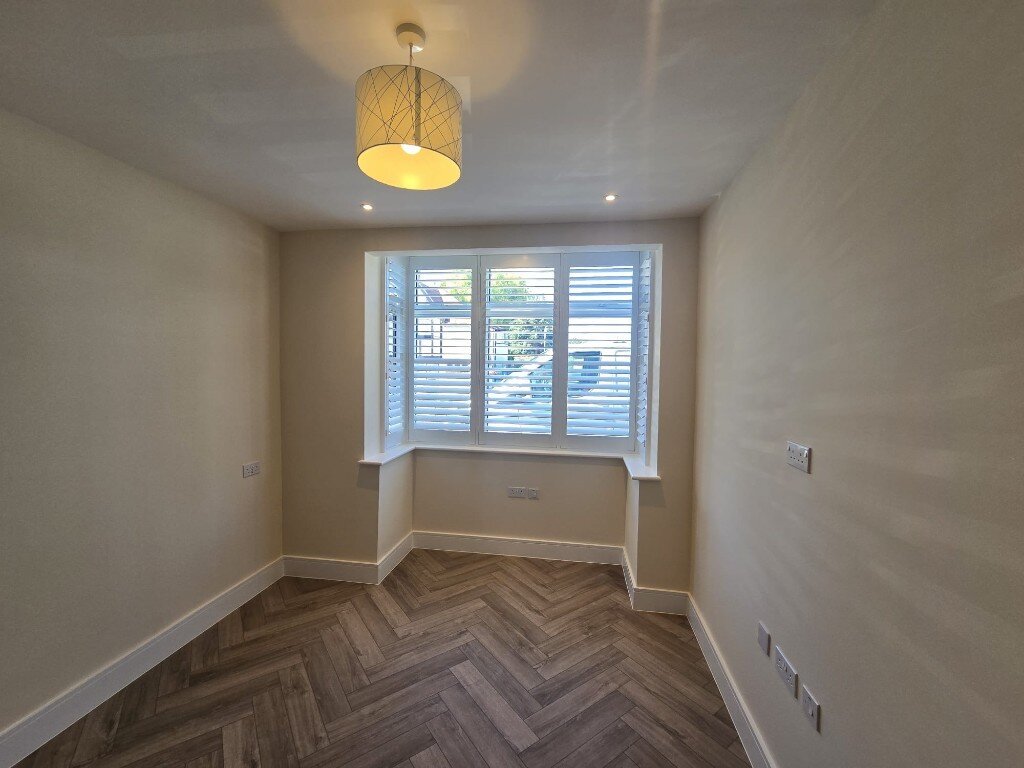 Harrow bay window with white full-height shutters and a geometric pendant light