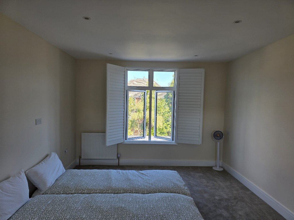 Full-height shutter panels folded open on a Harrow bedroom window