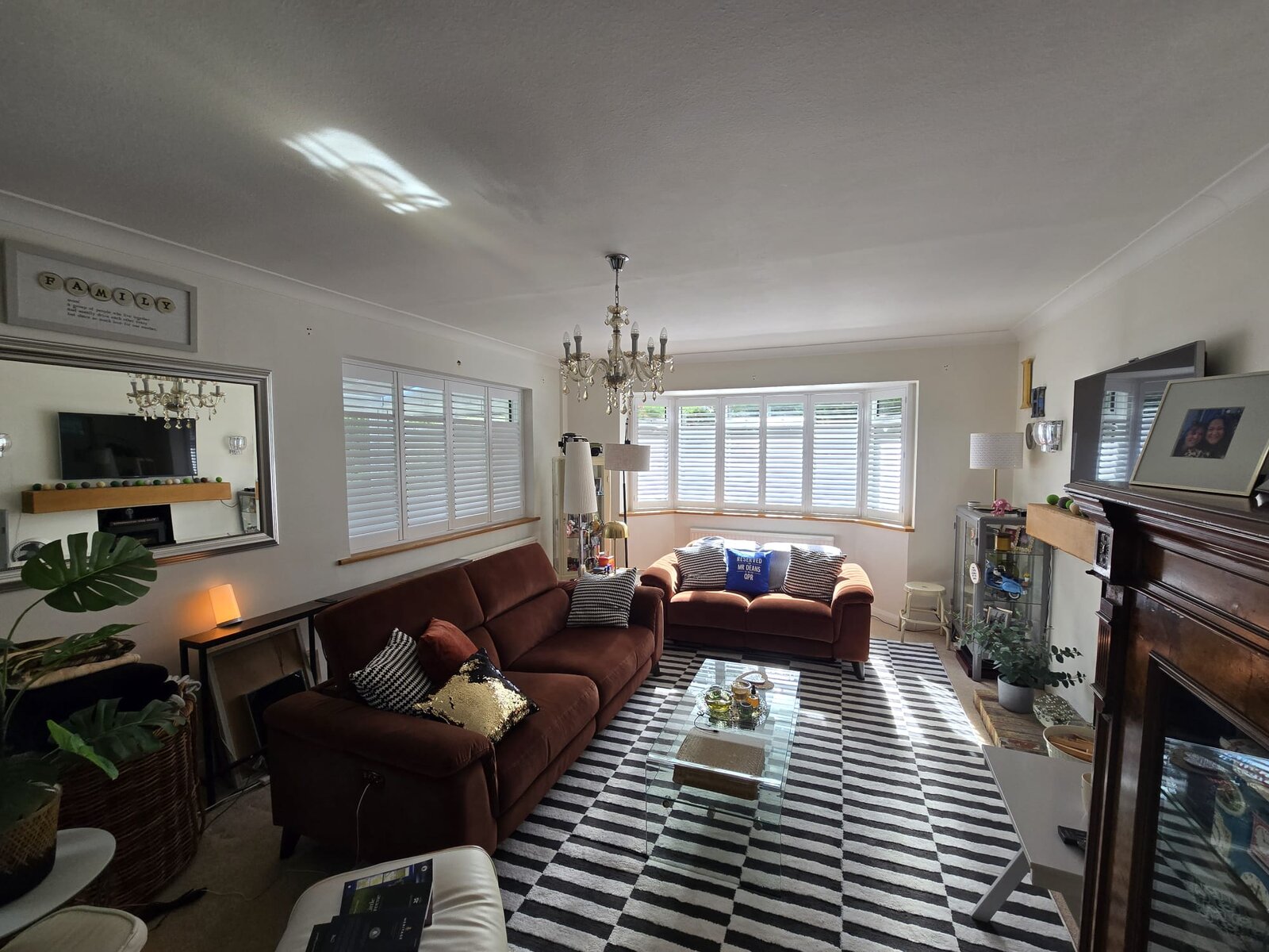 High Wycombe living room with white hardwood shutters on a bay window and a side window