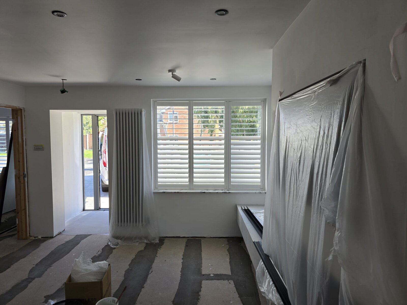 Three-panel white hardwood full-height shutters with hidden tilt on a Leamington Spa window