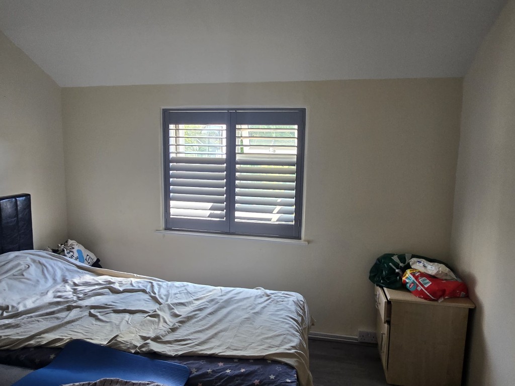 Pebble full-height polymer shutters on a bedroom window with louvres open