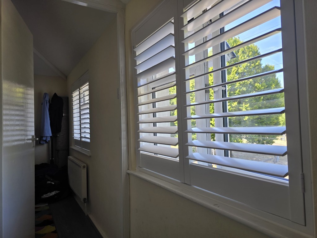 Two White full-height polymer shutter windows along a bright hallway