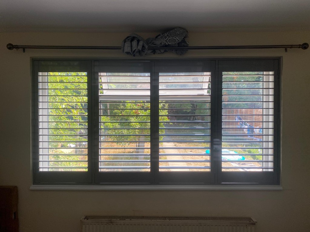 Wide four-panel Pebble full-height polymer shutters overlooking a garden