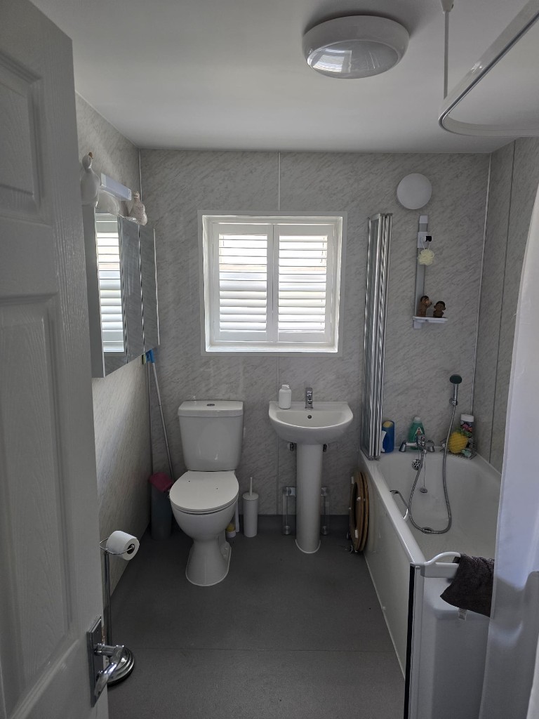 Snow White full-height hardwood shutters on a bathroom window above a pedestal sink