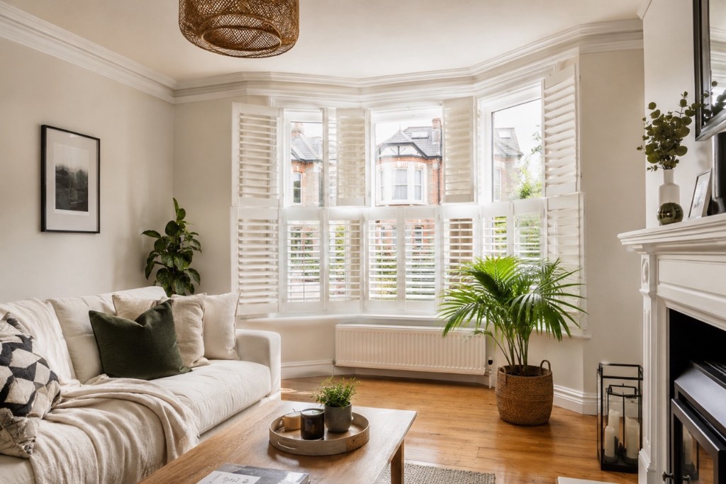 White tier-on-tier plantation shutters on a Georgian style bay window in an Oxfordshire living room
