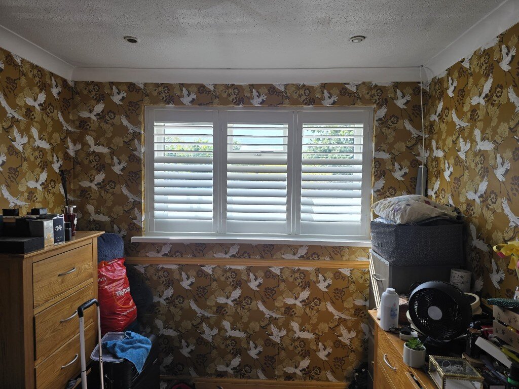 Full-height shutters with hidden split — top louvres open, lower louvres closed — in a Twickenham bedroom