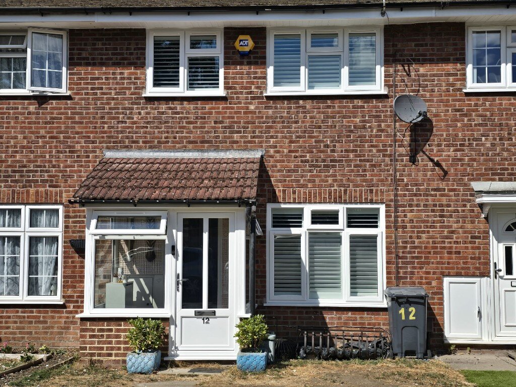 White full-height shutters on the front windows of a red-brick Twickenham terrace