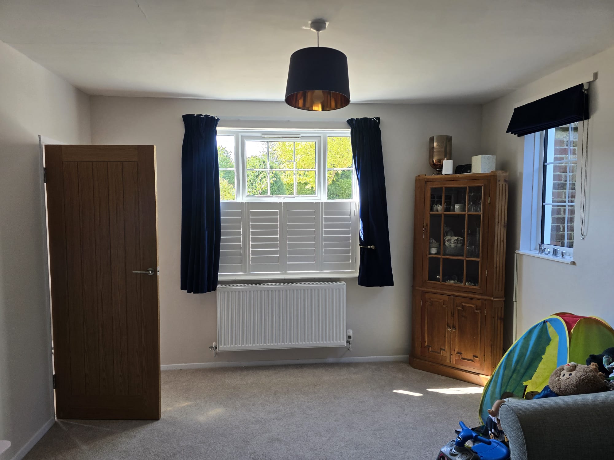 Interior view of white café-style hardwood shutters in a bright Winchester living room